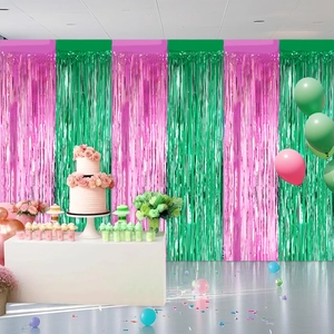 Pink and green tinsel curtain backdrop setup with party decorations and balloons