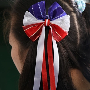 Detail of red white and blue bow hair tie with glitter embroidery on a model's long hair