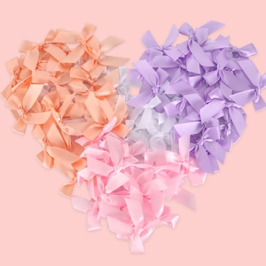 Mini satin ribbon bows in macaron colors arranged in a heart shape for DIY crafts