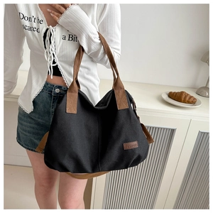 Detail of black canvas tote bag with brown fashion patch and sturdy fabric handles