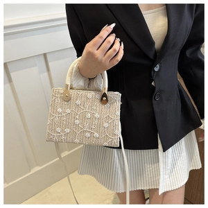 Detail of straw woven bag with white floral embroidery and gold metal buckle hardware