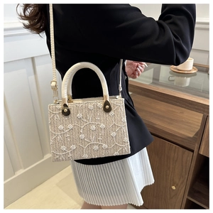 Close-up of cream woven straw bag featuring delicate white floral embroidery and gold hardware