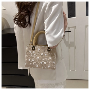 Detail of woven straw handbag with floral embroidery and yellow leather strap