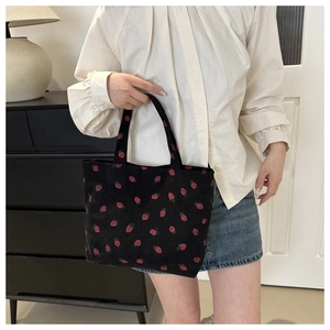 Detail of black corduroy tote bag with strawberry patterns and ribbed texture detail