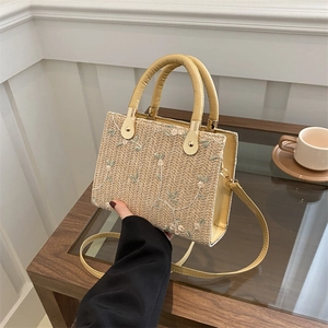 Fashionable woven straw crossbody bag with floral embroidery and cream leather straps