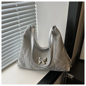 Detailed macro view of silver metallic bucket bag with butterfly buckle and pleated texture