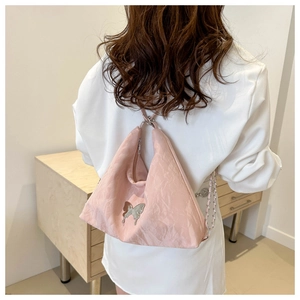 Détail d'un sac seau plissé rose avec breloque papillon argentée et bandoulière