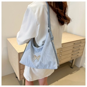 Détail du sac à bandoulière plissé bleu clair avec boucle papillon en métal argenté