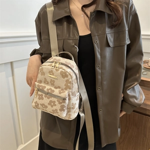 Mini floral canvas bucket backpack with adjustable straps worn by a female model