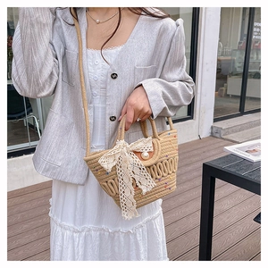 Détail du sac en paille avec nœud en dentelle blanche, bouton perle et pois colorés