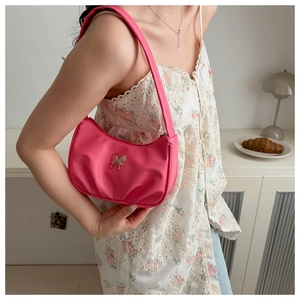 Sac hobo rose avec boucle papillon argentée porté par un mannequin en robe fleurie