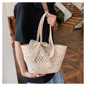 Détail du sac cabas beige tressé avec des pois colorés et un nœud en dentelle élégant