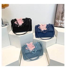 Detailed view of three denim shoulder bags with pink frayed star patch and plastic chain