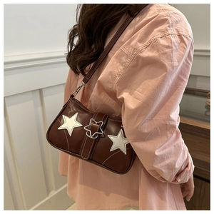 Detail view of brown denim shoulder bag featuring white star patches and metal buckle