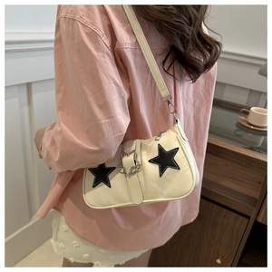 Side view of cream shoulder bag with black star patches and star-shaped metal buckle