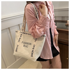 Detail of off-white canvas tote bag with black Fashion Bag lettering and dual straps