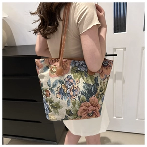 Dettaglio della borsa tote jacquard floreale con tracolla in pelle marrone su modella
