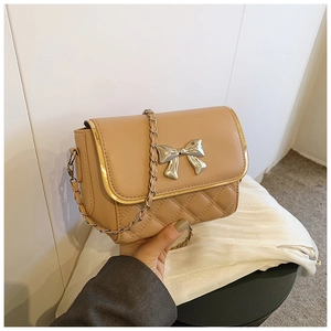 Detail of beige quilted mini crossbody bag featuring a silver bow buckle and gold chain