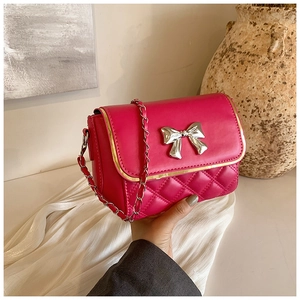 Detail of rose red quilted chain bag with silver bow and gold metal edge trim on flap