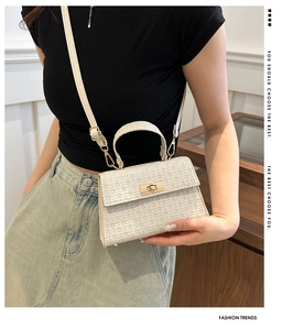 Detailed view of white woven crossbody bag featuring a golden metal twist-lock and strap