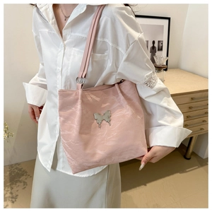 Close-up of pale pink nylon tote with a silver butterfly ornament worn by a model