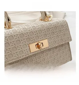 Detail shot of beige woven leather texture and gold twist-lock buckle on the small flap bag