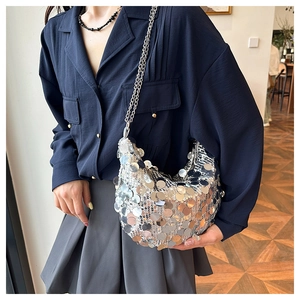 Close-up of shiny silver sequins on a stylish hobo bag with a delicate metal chain strap