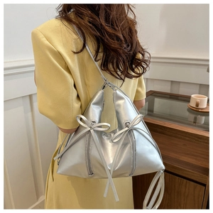 Dettaglio di una borsa a secchiello triangolare argento con fiocchi su una modella