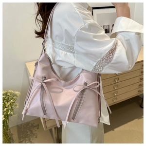 Dettaglio borsa a secchiello rosa chiaro con fiocco decorativo e accenti di zip argentate