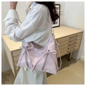 Dettaglio della borsa a tracolla rosa chiaro con fiocco elegante e zip metalliche