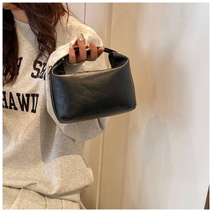 Détail d'un sac à main noir avec lettrage gaufré et poignée supérieure élégante