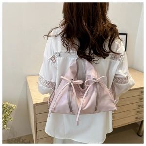 Dettaglio dello zaino in nylon rosa con fiocchi e cerniere mostrato su una modella