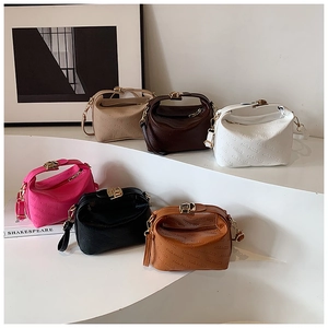 Six sacs polochons en cuir gaufré de différentes couleurs sur des socles minimalistes
