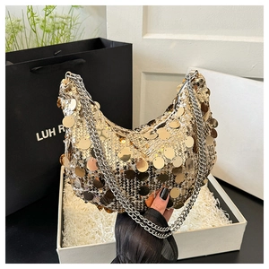 Close-up of golden circular sequins and silver chain strap on a crescent shoulder bag