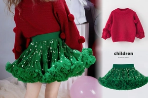 Detail of red knit sweater with 3D pompoms and green tutu skirt with gold stars