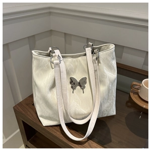 Chic cream tote bag with marble texture and silver butterfly buckle on wooden bench