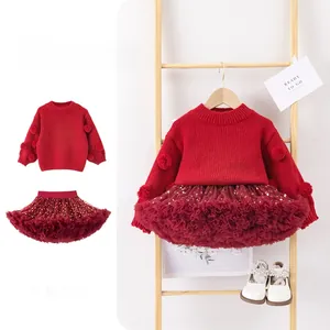 Detail of red knitted sweater with 3D pompoms and layered star sequin tulle skirt