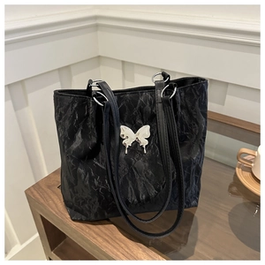 Close-up of black pleated fabric tote bag featuring a metallic silver butterfly clasp