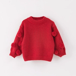 Detail of red knit sweater featuring festive pom-poms on sleeves and ribbed collar