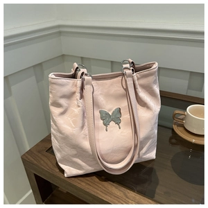 Close-up of light pink tote bag with metallic liquid butterfly detail and soft pleats