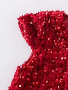 Dettaglio dell'abito in velluto rosso per bambine con paillettes e spalla a pieghe