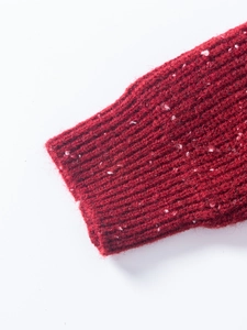 Close-up of red tweed knit sweater sleeve with ribbed cuff and white flecked texture