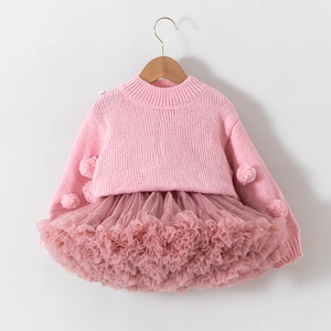 Detail of pink knitted sweater with pom-poms and tiered tulle tutu skirt for girls