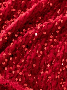 Dettaglio macro di paillettes rosse scintillanti su velluto per abiti da festa da bambina