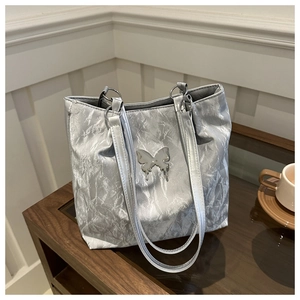 Close-up of silver pleated tote bag featuring a metallic texture and butterfly ornament