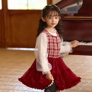 Detalle de vestido de tweed rojo con falda de tul y mangas de linterna para niña junto al piano