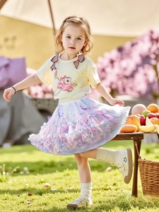 Détail d'un t-shirt jaune avec ourson et d'une jupe tutu en tulle dégradé violet pour filles