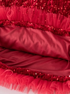 Vista dettagliata del ricamo di paillettes rosse e strati di tulle sul vestito da bimba