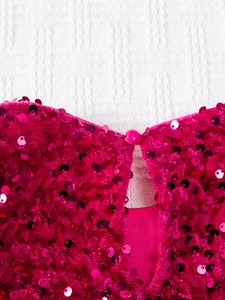 Détail de la robe à paillettes rose fuchsia avec découpe goutte et bouton de fermeture