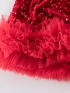 Dettaglio di paillettes rosse e balze di tulle a strati sull'abito festivo da ragazza
